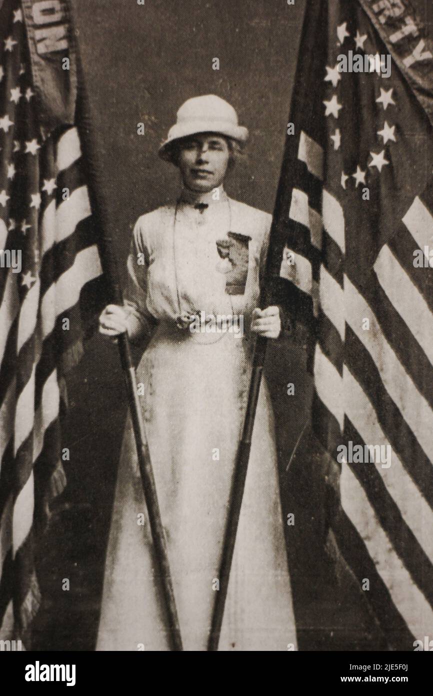 Una donna che indossa il suo abito e cappello domenica migliore mentre tiene due bandiere Betsy Ross Stati Uniti d'America in una stampa seppia. Foto Stock