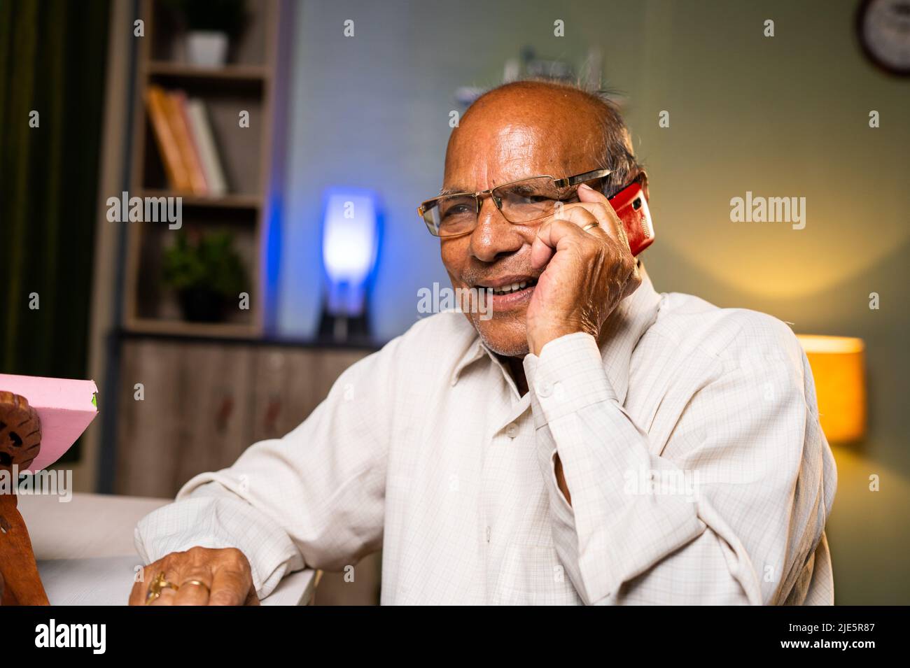 Felice sorridente anziano che parla sul telefono cellulare a casa - concetti di tecnologia, relax e comunicazione Foto Stock