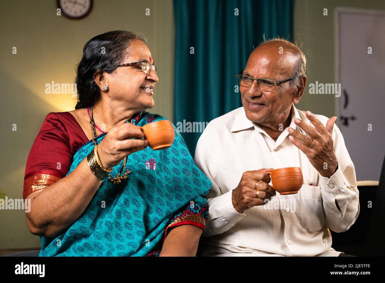 Coppia anziana felice che ha il tè mentre si parla a casa - concetto di felicità, rinfresco e stile di vita pensionamento Foto Stock