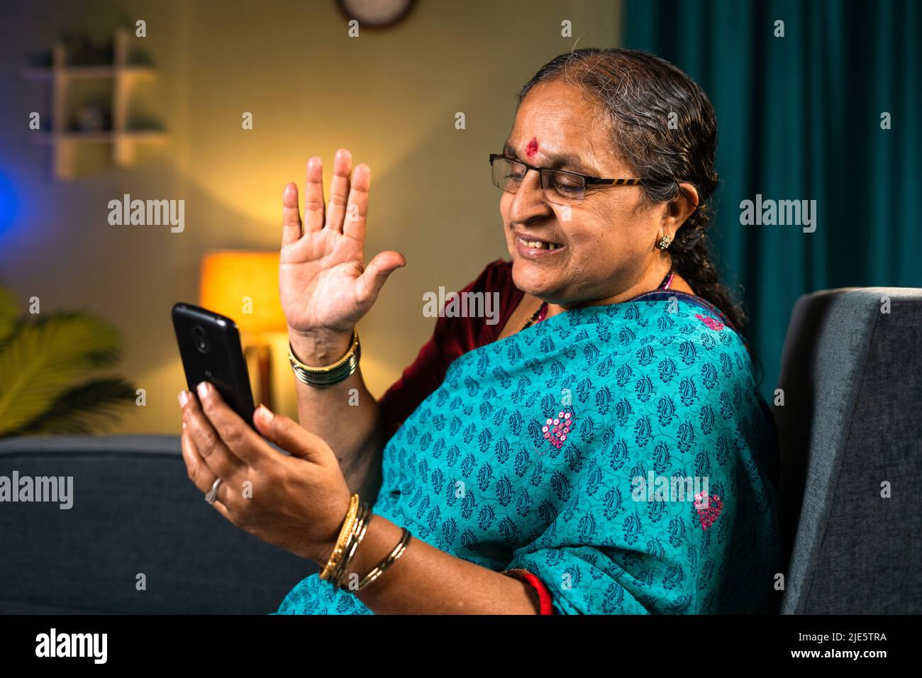 Le donne anziane fanno videochiamate sul telefono cellulare mentre si siedono sul divano a casa - concetti di tecnologia, relax e divertimento. Foto Stock