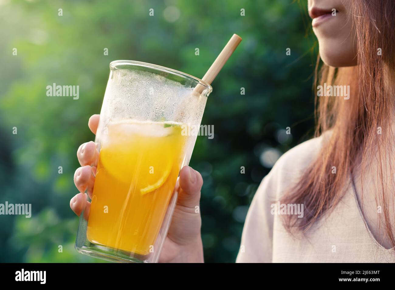 Ragazza che tiene il bicchiere con fresco cocktail estivo arancione, primo piano, fuoco selettivo. Foto Stock