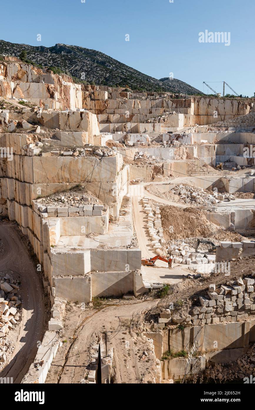 Pareti rocciose, rampe, blocchi ed escavatori nella cava di marmo vicino Orosei sulla costa orientale della Sardegna, Baronia, Italia Foto Stock