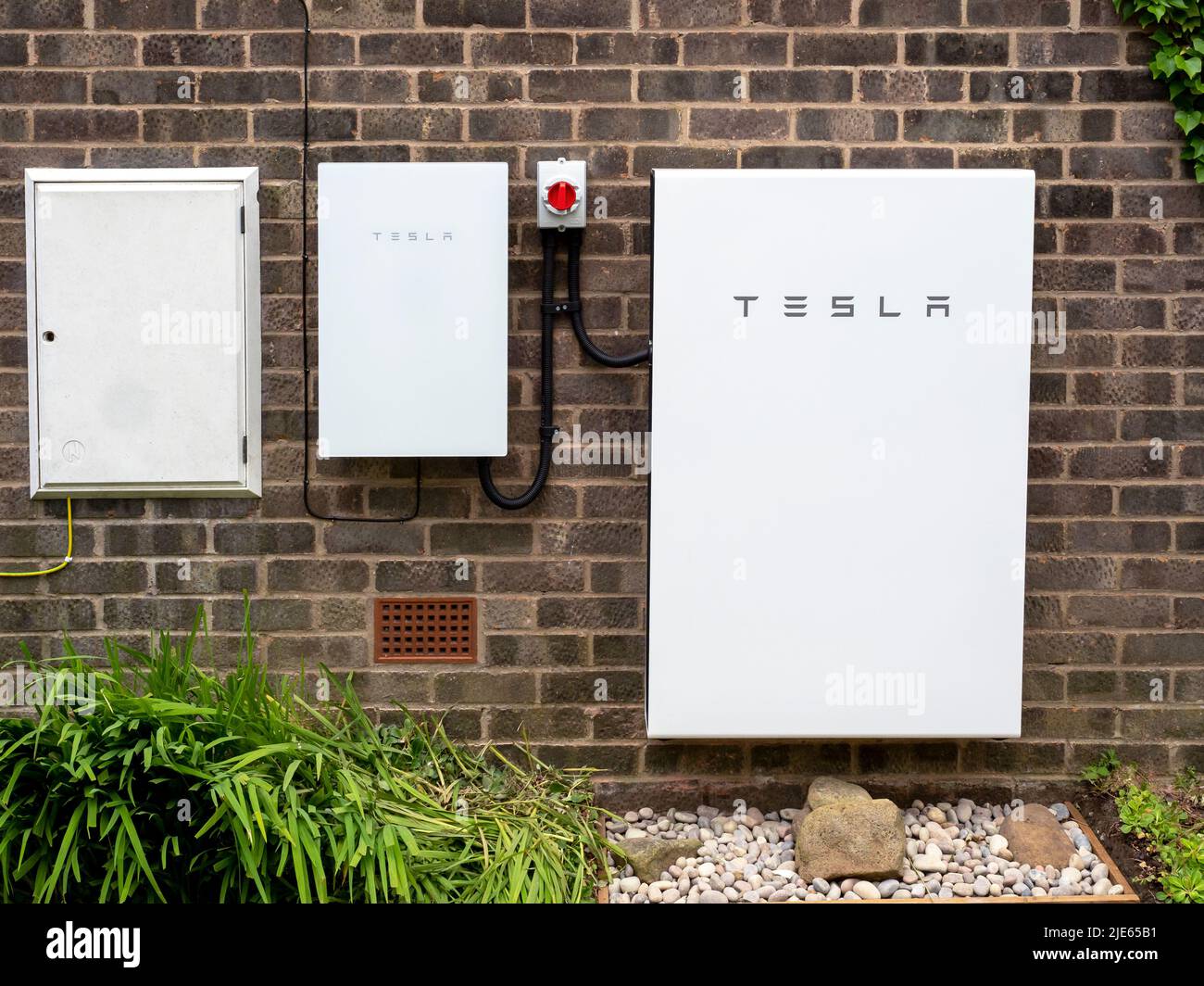 Sistema di stoccaggio delle batterie Tesla Powerwall 2 e Backup Gateway 2 installato su una parete di un edificio in mattoni Foto Stock