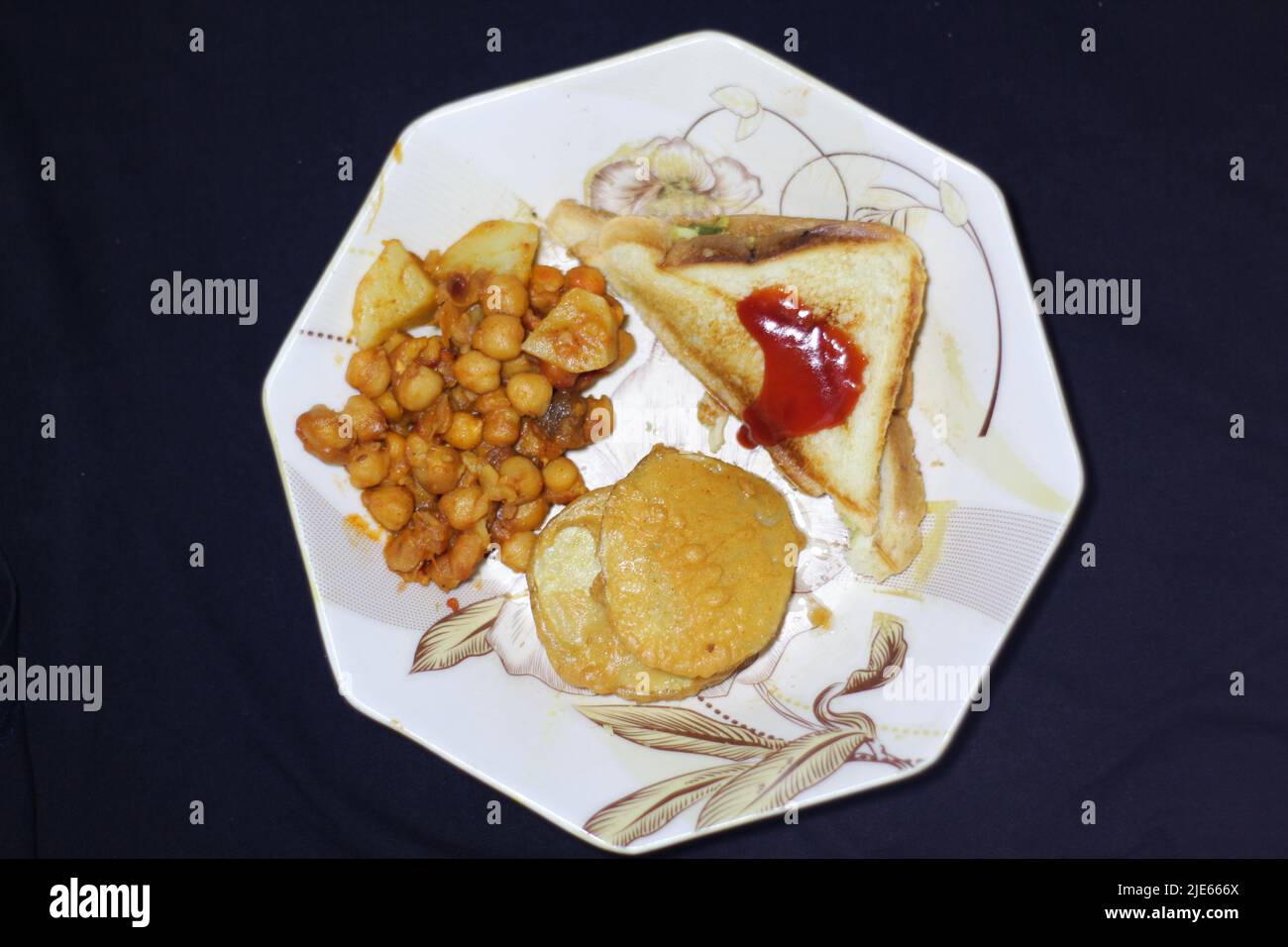 Deliziosa colazione nel piatto sandwich Cholay Bhature nel piatto su sfondo nero Punjab Lahore Pakistan Foto Stock