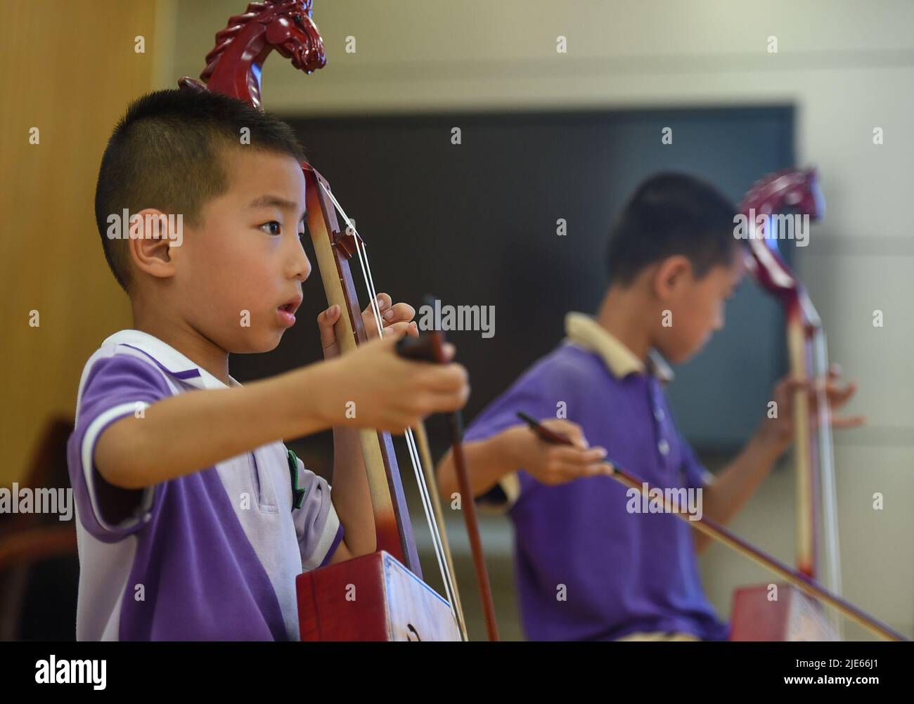 (220625) -- BAOTOU, 25 giugno 2022 (Xinhua) -- gli studenti imparano a suonare Morin khuur, un tradizionale strumento ad arco mongolo che presenta un'incisione con testa di cavallo nella sua parte superiore, durante un'attività post-lezione in una scuola primaria a Baotou, nella Regione Autonoma Mongolia interna della Cina settentrionale, 24 giugno 2022. Le scuole di Baotou hanno organizzato varie attività dopo le lezioni per arricchire il tempo scolastico degli studenti. (Xinhua/Peng Yuan) Foto Stock