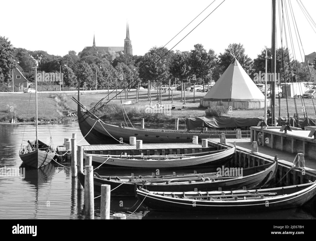 Immagine monocromatica delle barche ormeggiate al Molo del Museo delle navi Vichinghe con la Cattedrale di San Luca sullo sfondo, Roskilde, Danimarca Foto Stock