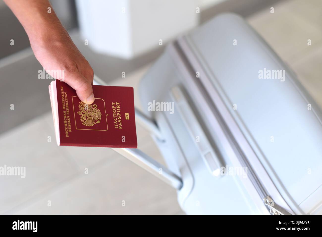 Una mano con passaporto russo e valigia Foto Stock