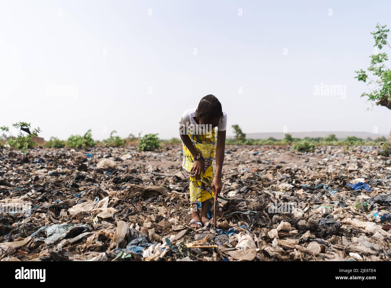 La giovane ragazza africana si scava in una discarica di rifiuti alla ricerca di materiale riutilizzabile; riciclaggio informale dei rifiuti Foto Stock