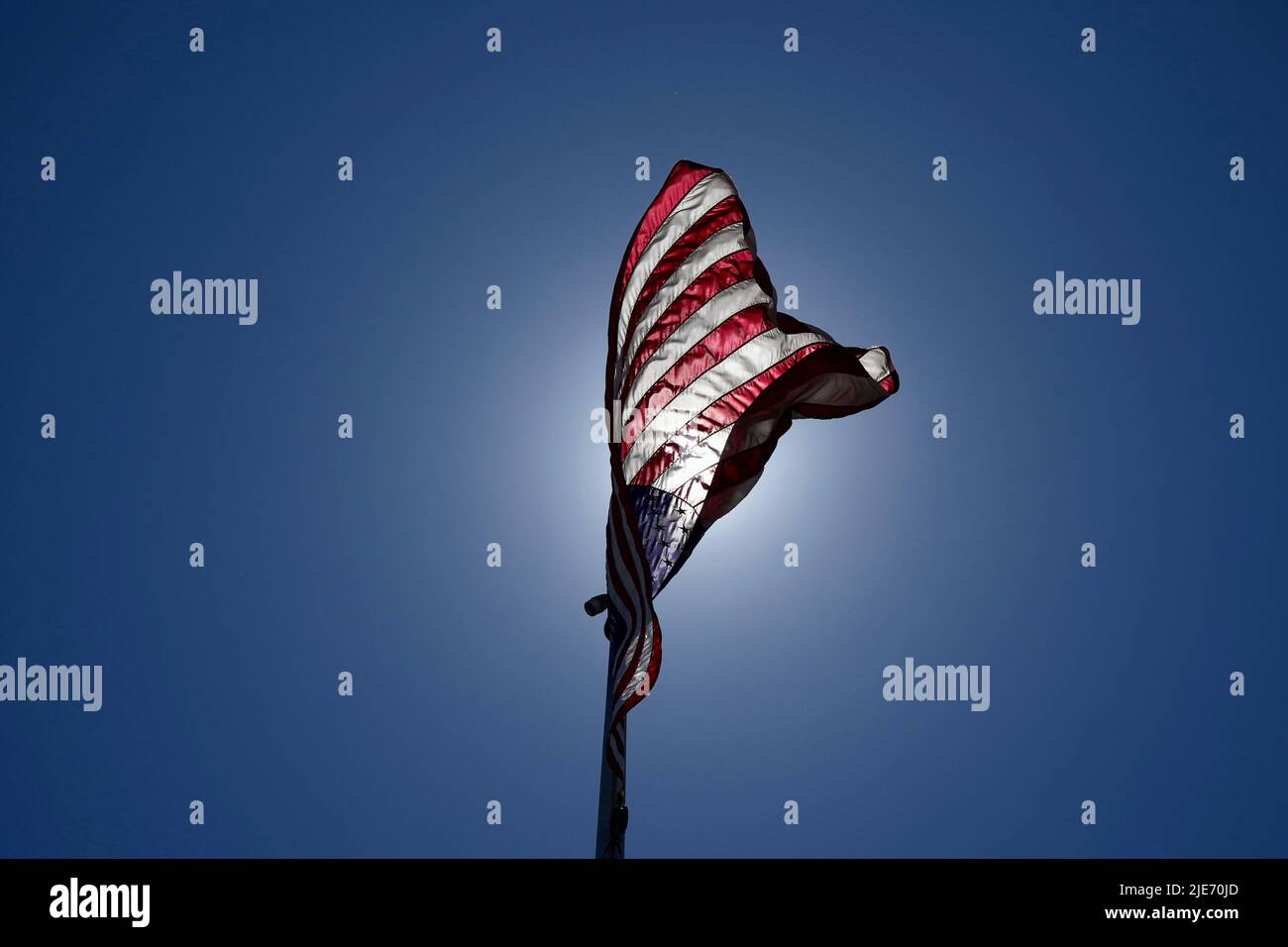 Una vista ad angolo basso di una bandiera americana riaccesa dal sole che soffia nel vento. Foto Stock