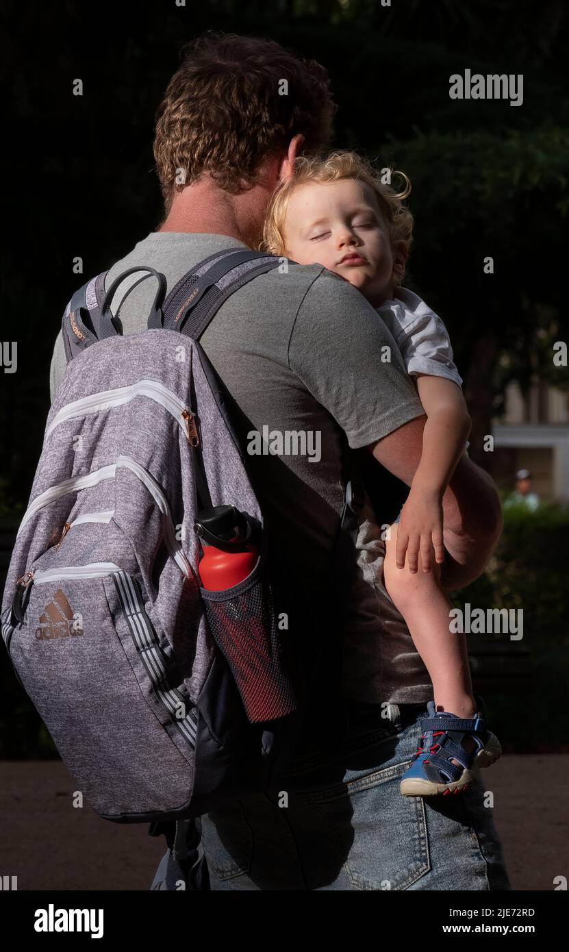 Padre tiene il bambino addormentato in braccio in un parco di Lisbona Foto Stock