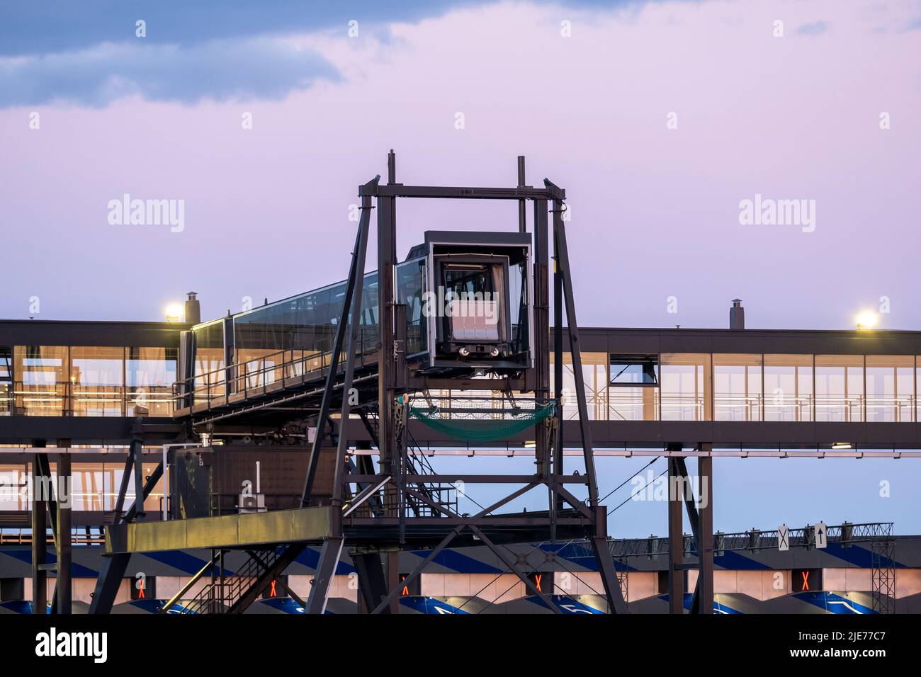 primo piano di un moderno terminal delle navi da crociera con un ponte di imbarco passeggeri in vetro contro un cielo vivido durante il tramonto Foto Stock