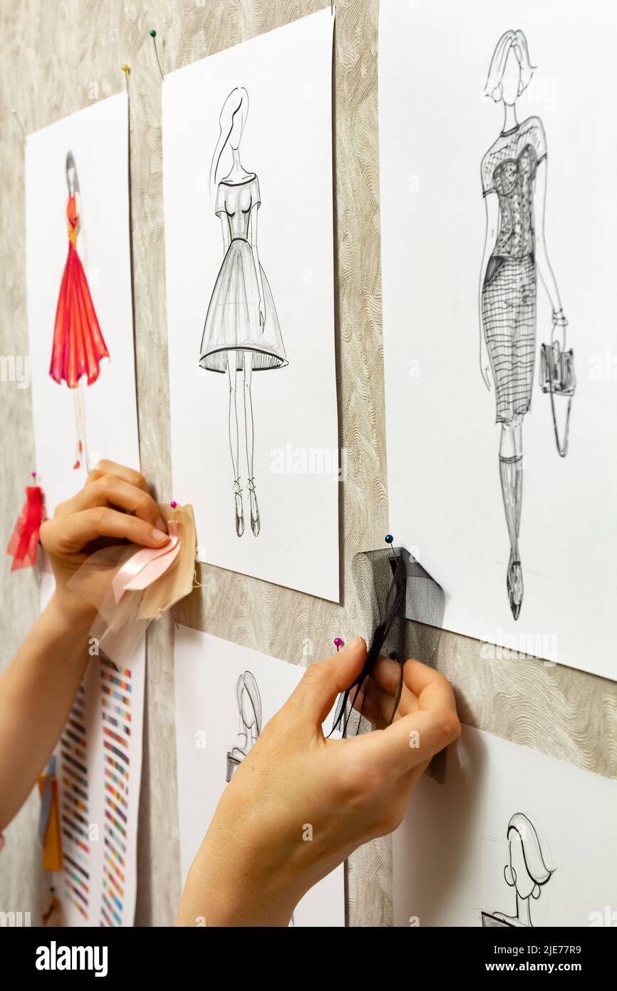 Il fashion designer sviluppa schizzi di design di abbigliamento. L'artista crea abiti da donna. Lavorare su misura con il tessuto. Foto Stock