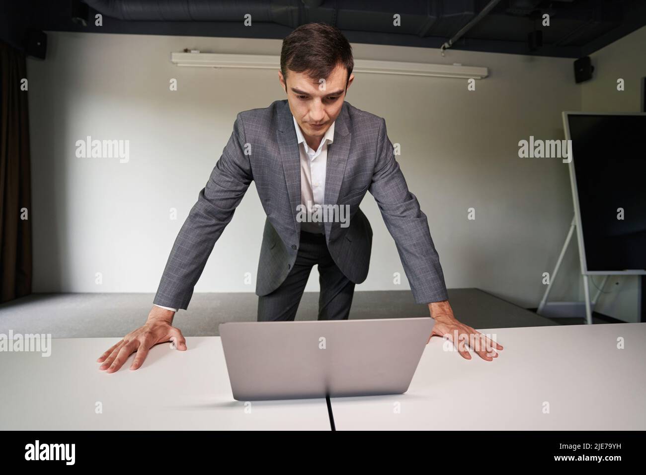 Uomo serio che si appoggia sul laptop sul tavolo in ufficio Foto Stock