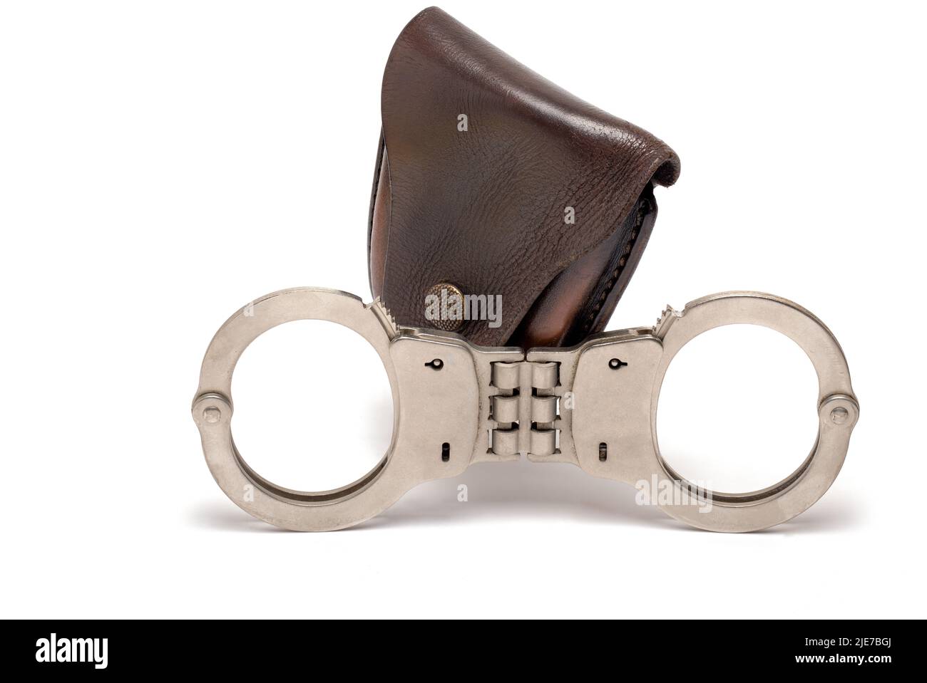 Primo piano Police ferro manette in acciaio con pezzo intermedio rigido di fronte alla custodia in pelle scura chiuso polso bloccaggio barre su sfondo bianco A. Foto Stock Primo piano Police ferro manette in acciaio con pezzo intermedio rigido di fronte alla custodia in pelle scura chiuso polso bloccaggio barre su sfondo bianco A. Foto Stock