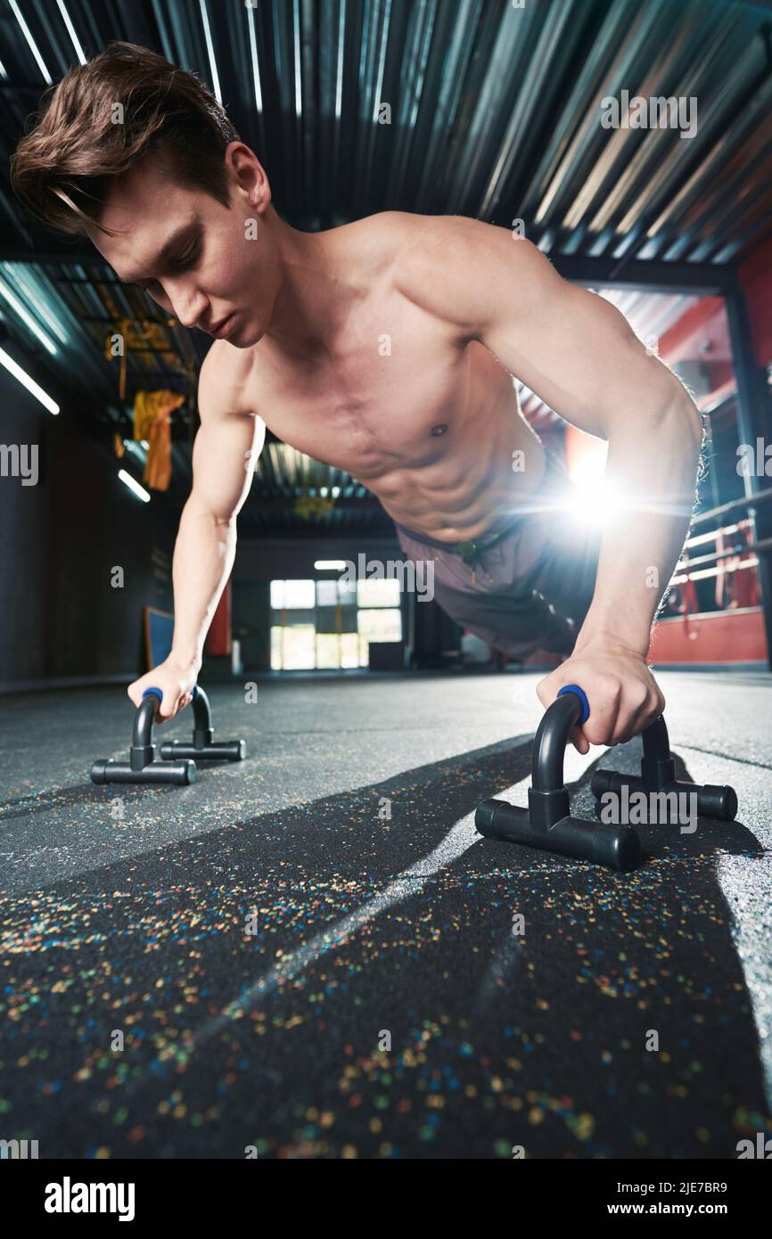 Concentrato forte ben costruito giovane uomo che esegue press-up Foto Stock