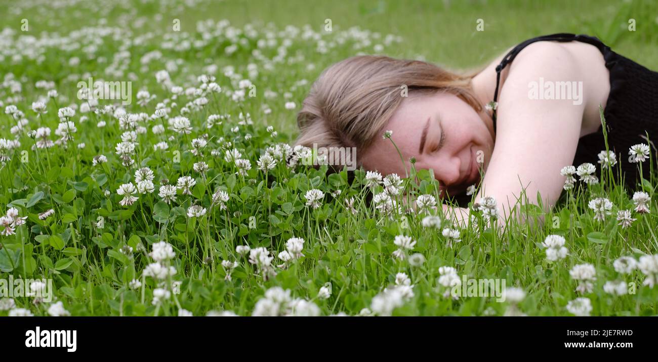 Donna stesa su erba verde e sorridente Foto Stock