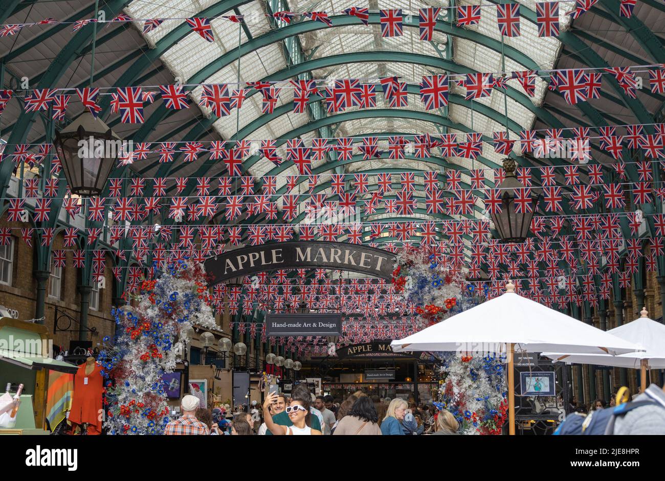 Apple Market a Covent Garden Londra con Union Jack Flags appeso al soffitto, e i turisti che visitano la città. Foto Stock