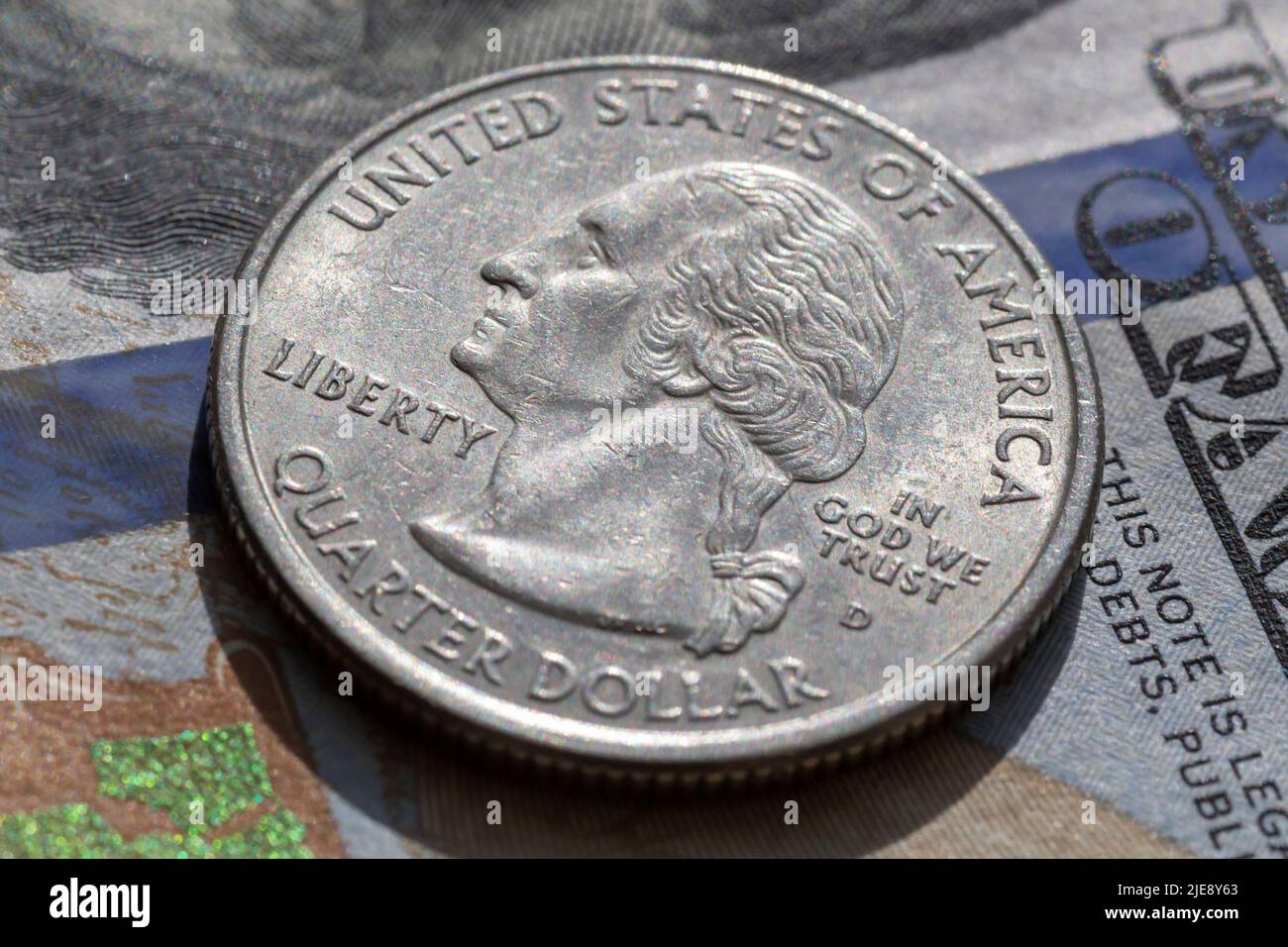 primo piano della moneta da un quarto di dollaro che giace su una banconota da cento dollari Foto Stock