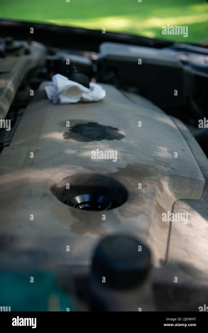Svitare il tappo dell'olio motore sul coperchio decorativo in plastica del motore sporco. Foto Stock