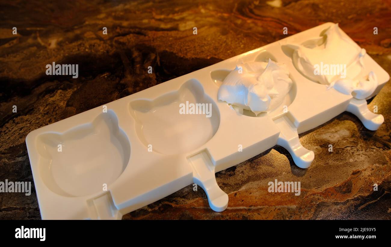 Fare le pistoncini fatte in casa. Uomo che versa il gelato in muffe freezer. Foto Stock