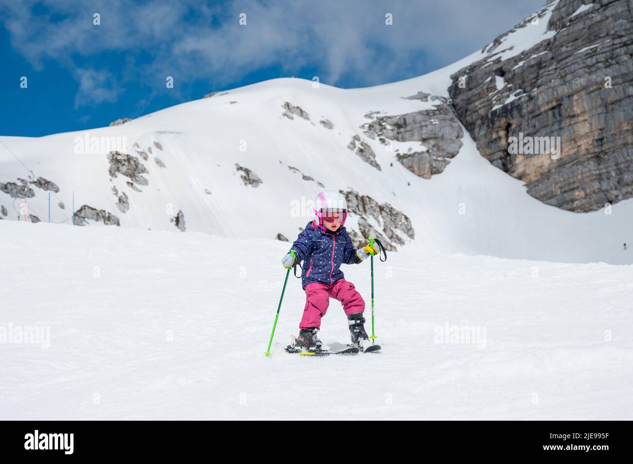 Ragazza simpatica che impara a sciare in una località invernale in una giornata di sole. Foto Stock