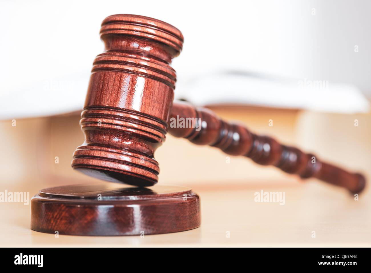 Libro di legge aperto con un gavel di legno dei giudici sul tavolo in una stanza di tribunale o nell'ufficio di applicazione della legge Foto Stock