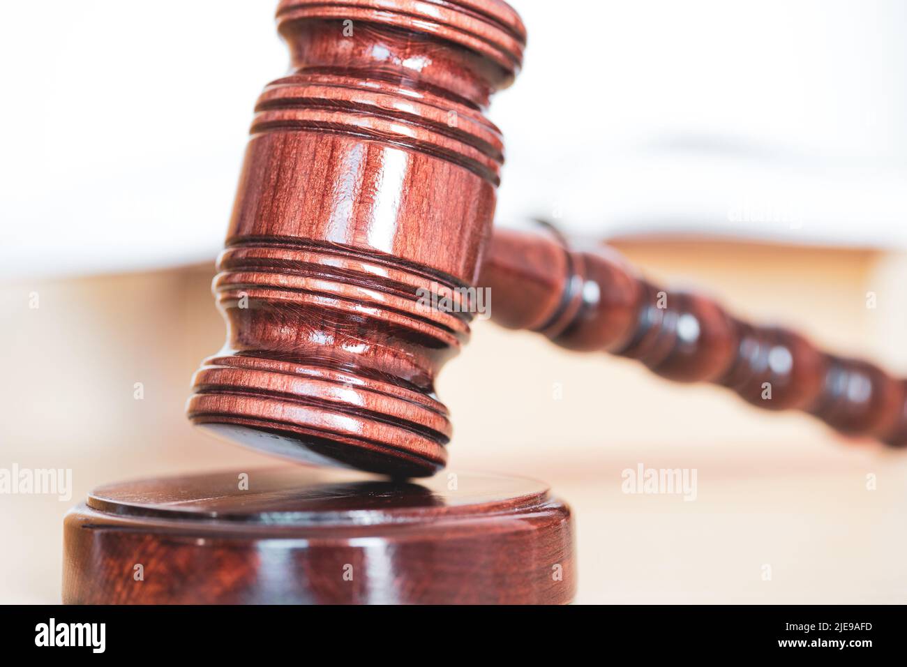 Libro di legge aperto con un gavel di legno dei giudici sul tavolo in una stanza di tribunale o nell'ufficio di applicazione della legge Foto Stock