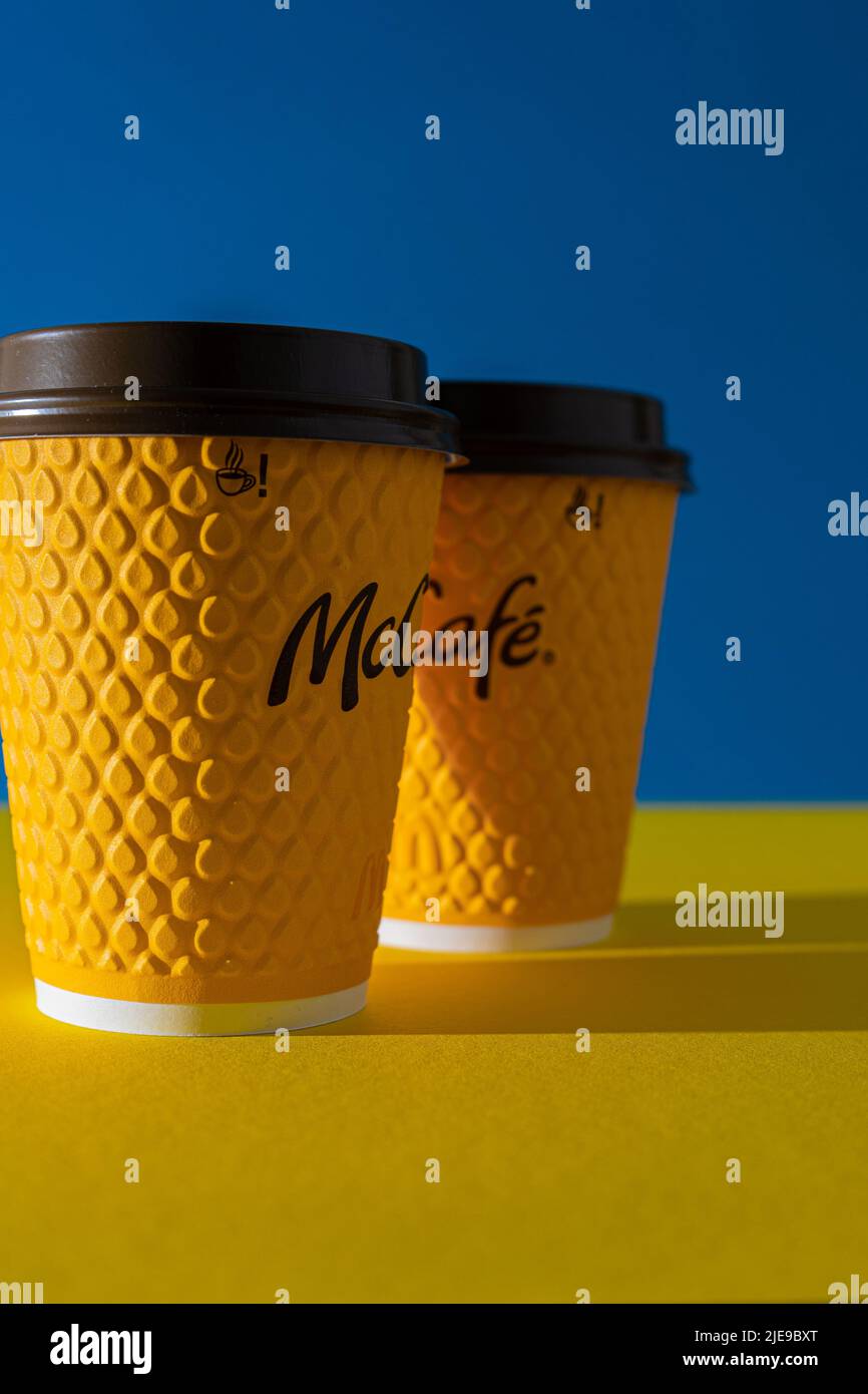 Ucraina, Kiev - 17 febbraio 2021: Bicchiere giallo di caffè da McDonald's. Bicchiere di carta bere McCafe. Tazza offee sul tavolo con ombre. Menu nel ristorante fast food. Foto Stock