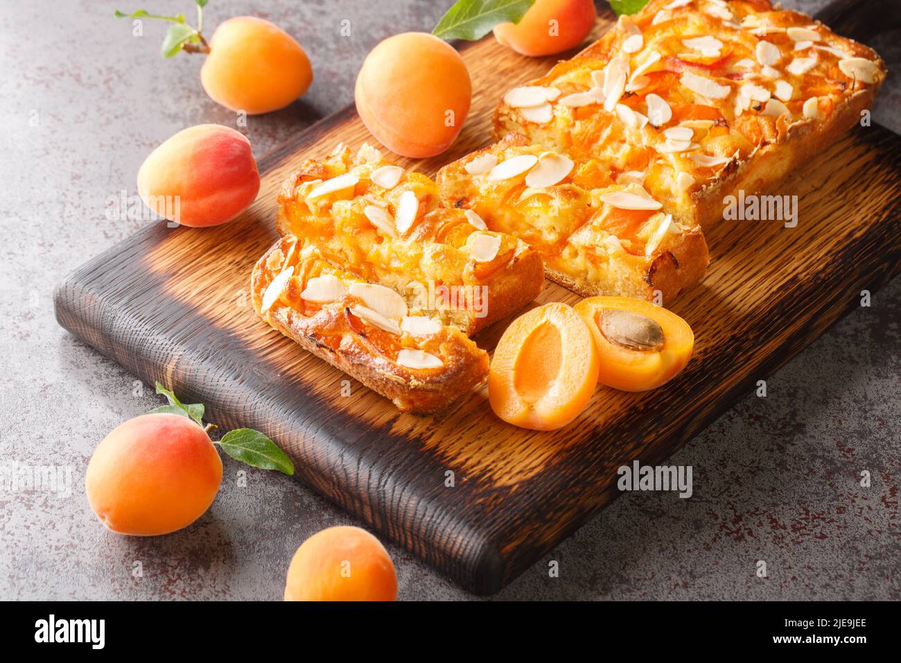 Estate torta di albicocche fresche con mandorle da vicino su un asse di legno sul tavolo. Orizzontale Foto Stock