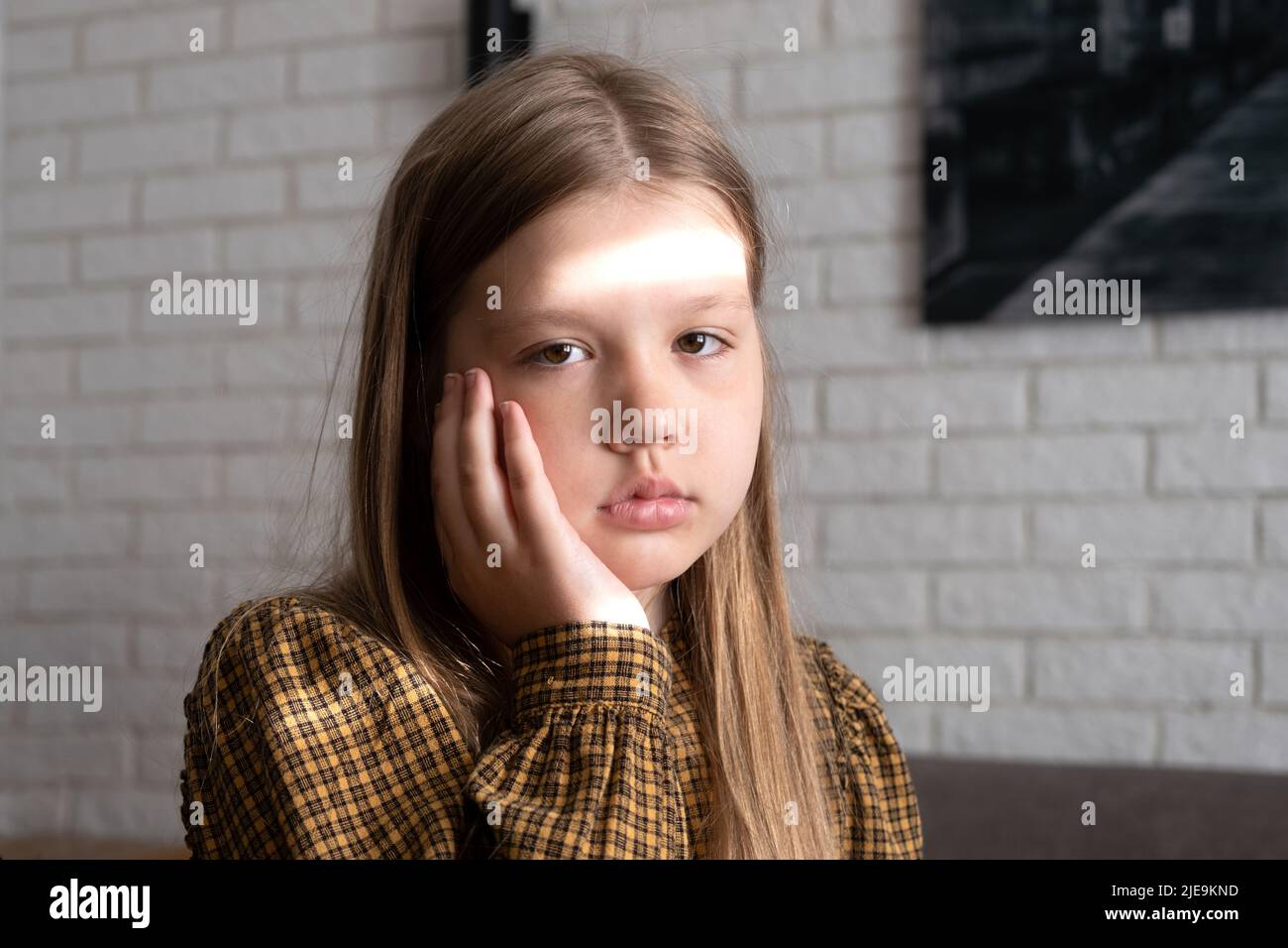 Bambina con mal di denti. Una bambina ha una guancia gonfia a causa di un mal di denti. La bambina tiene la guancia e il dente fa male Foto Stock