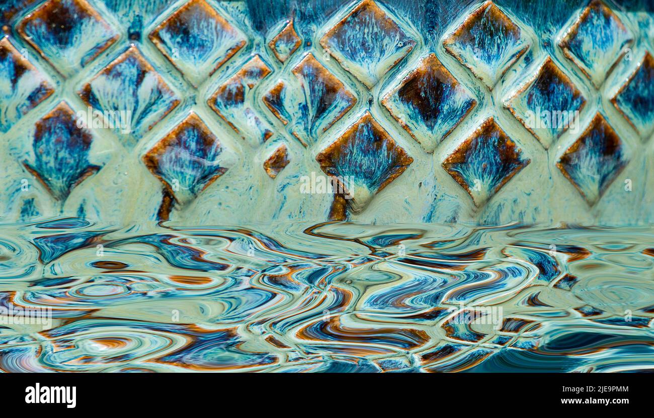 Astratto disegno a forma di diamante blu acqua con il suo riflesso in acqua Foto Stock
