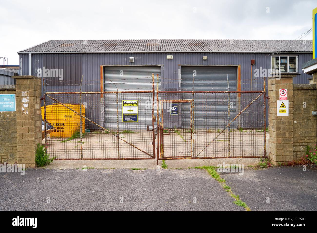 Cancelli chiusi arrugginiti all'ingresso di un composto shabby su una tenuta industriale Foto Stock