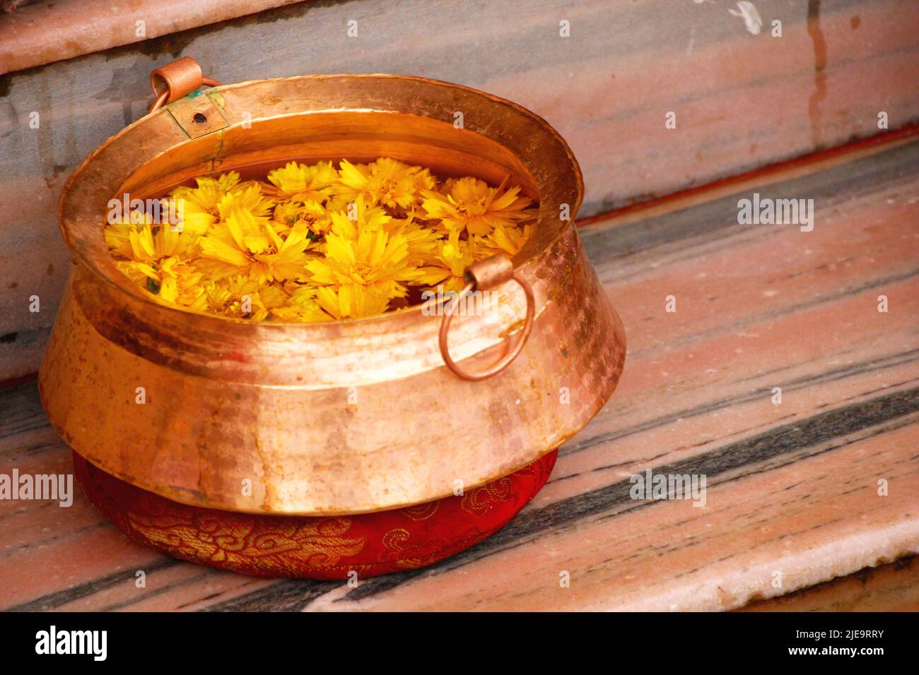 Immagine di un contenitore pieno di petali, rituale. Petali arancioni galleggianti sull'acqua all'interno di un contenitore metallico, immagine ravvicinata, primo piano Foto Stock