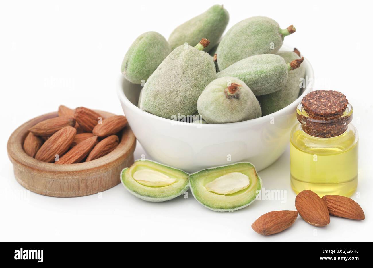Mandorla verde e pelata e olio essenziale su sfondo bianco Foto Stock