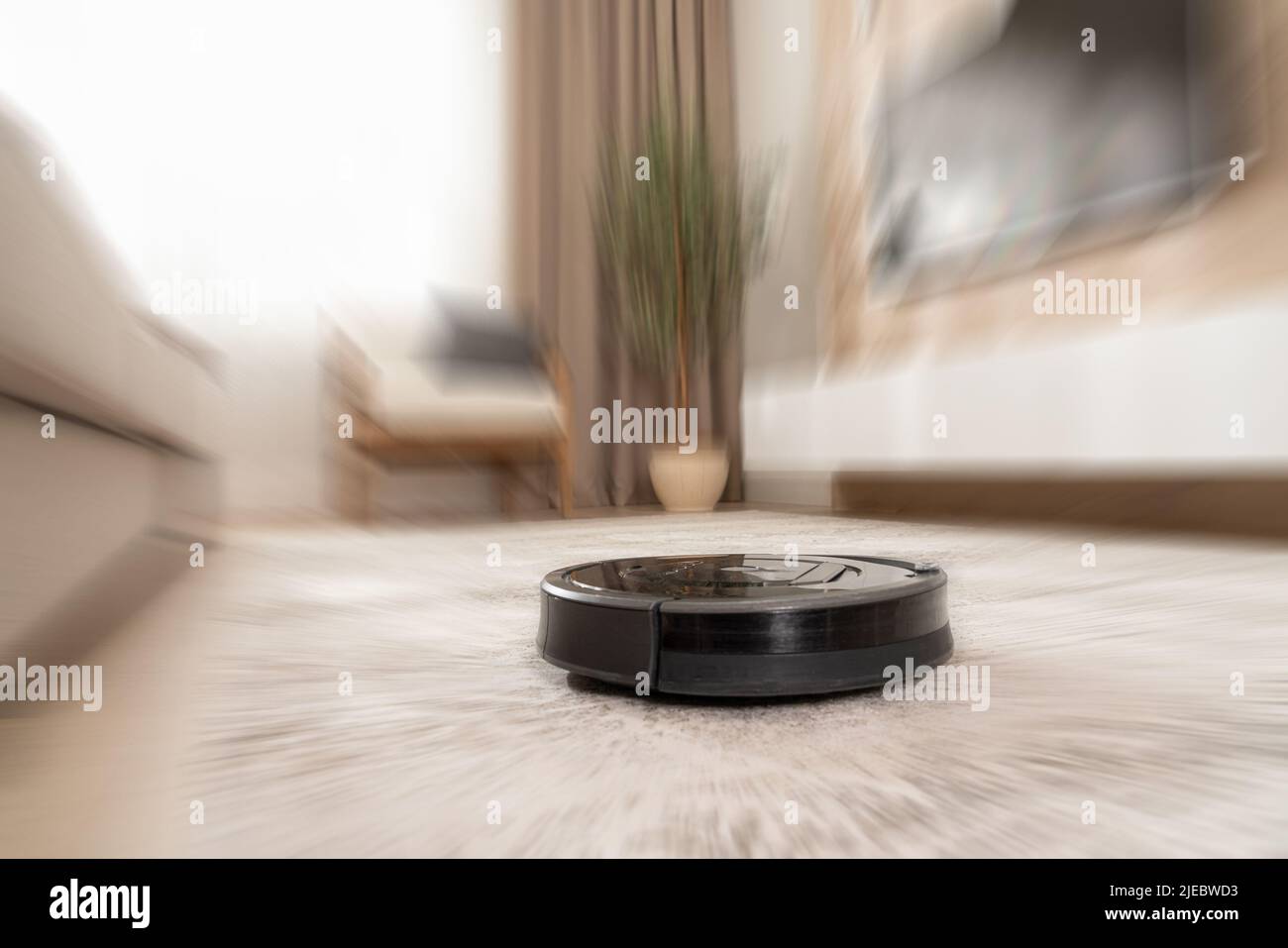 pulizia automatica dei tappeti in un moderno aspirapolvere robot con effetto motion blur Foto Stock