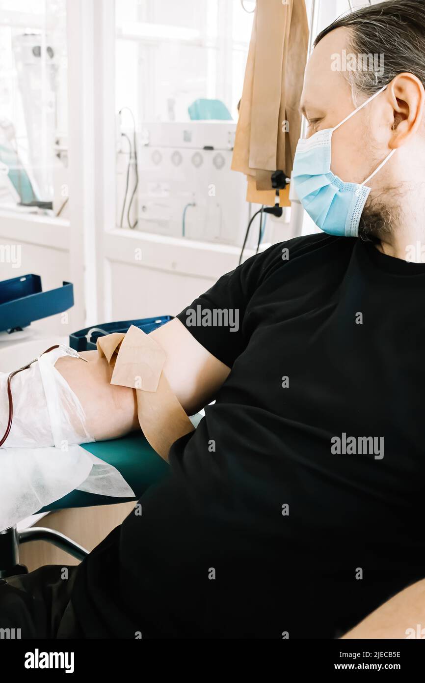 L'uomo di mezza età dona sangue in laboratorio medico. Il donatore di sangue dona sangue per salvare la vita e per la ricerca medica. Giornata internazionale della donazione di sangue. Foto Stock