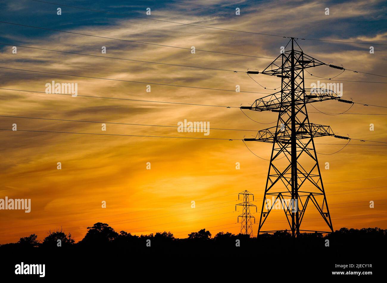 Silhouette di pilone di elettricità contro un caldo tramonto sulla campagna inglese. Foto Stock