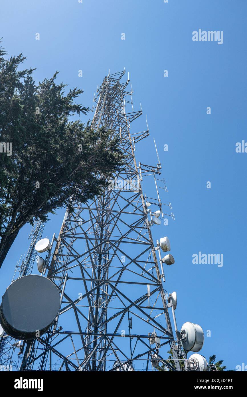 Un telefono cellulare e una torre di comunicazione a microonde contro il cielo blu Foto Stock