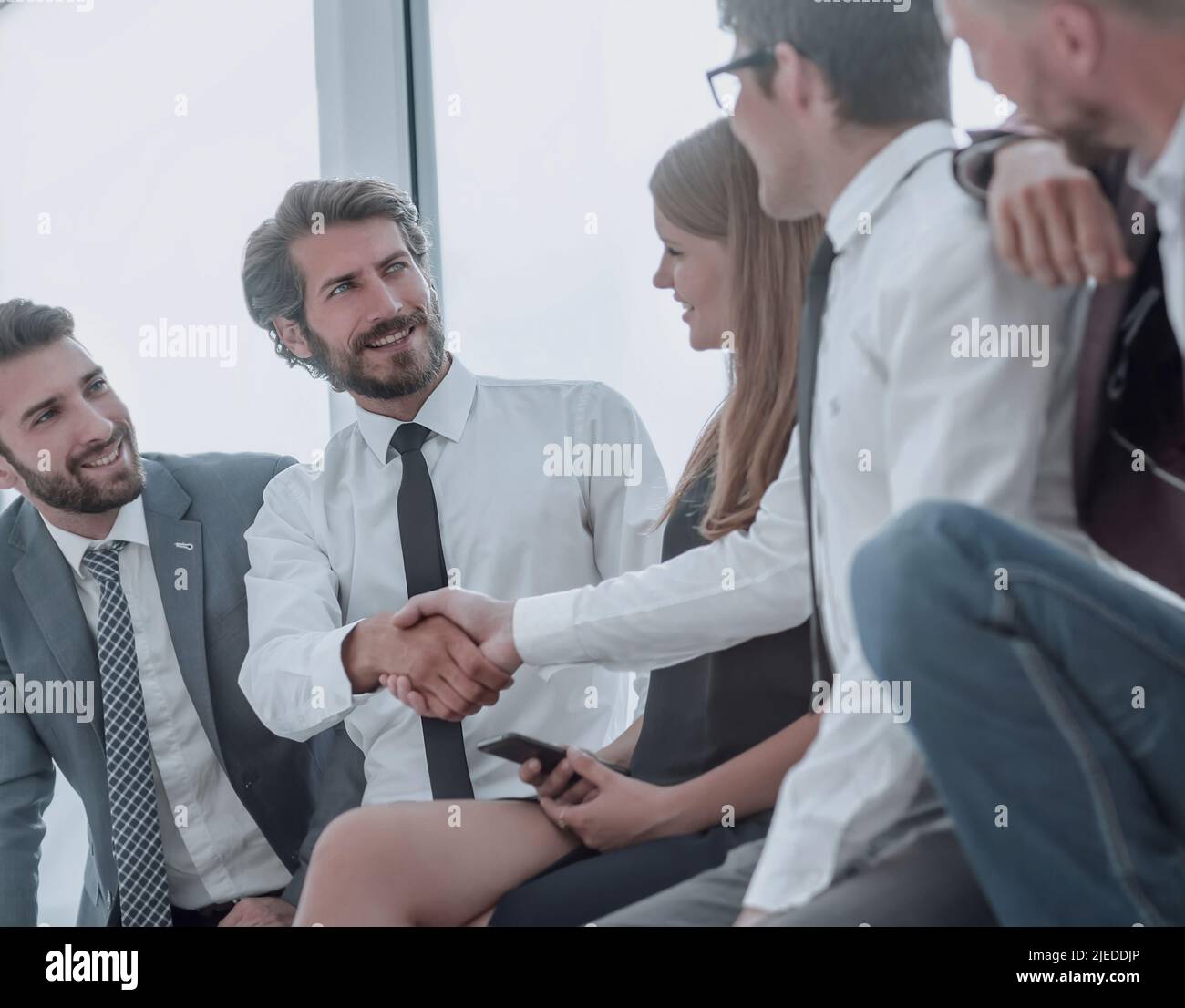 I giovani uomini di affari che stringono le mani mentre è seduto nella lobby di office Foto Stock