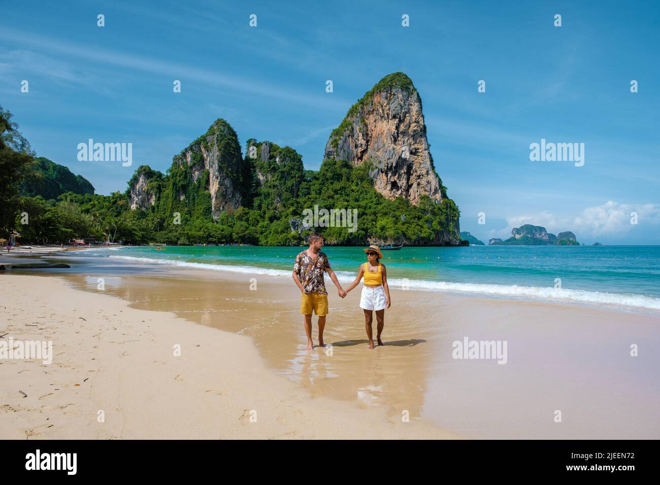 Railay Beach Krabi Thailandia, la spiaggia tropicale di Railay Krabi, un paio di uomini e donne sulla spiaggia, vista panoramica di idilliaca Railay Beach in Thailandia con una barca tradizionale lunga. Foto Stock