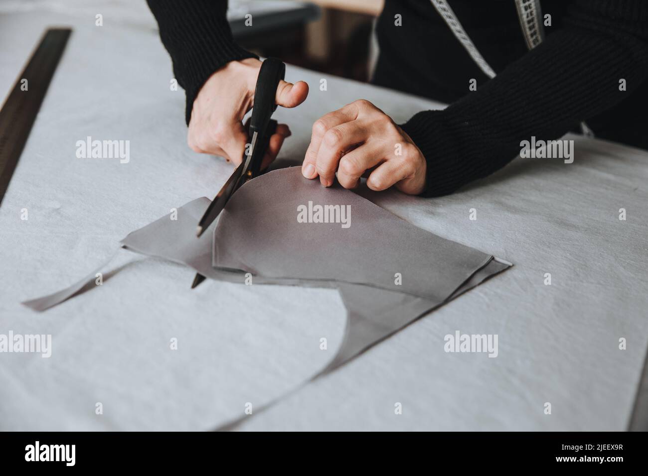 Design su misura per il taglio di un pezzo di stoffa con forbici, concetto imprenditore. Foto Stock