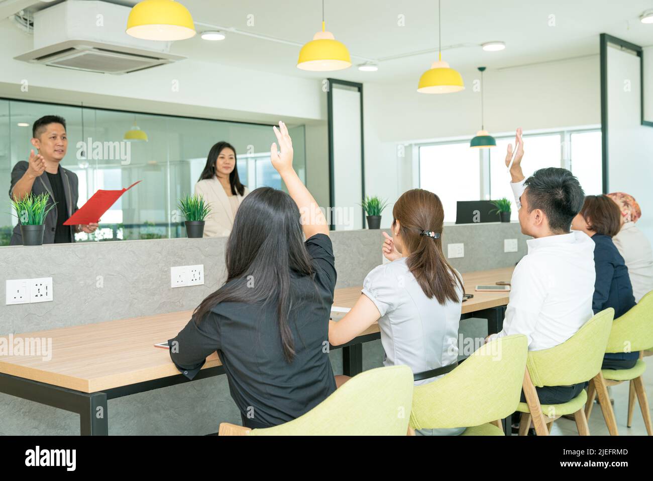 Formazione in ufficio in corso con tirocinanti che sollevano le mani per porre domande. Impostazione dell'ufficio co-lavorativo. Foto Stock
