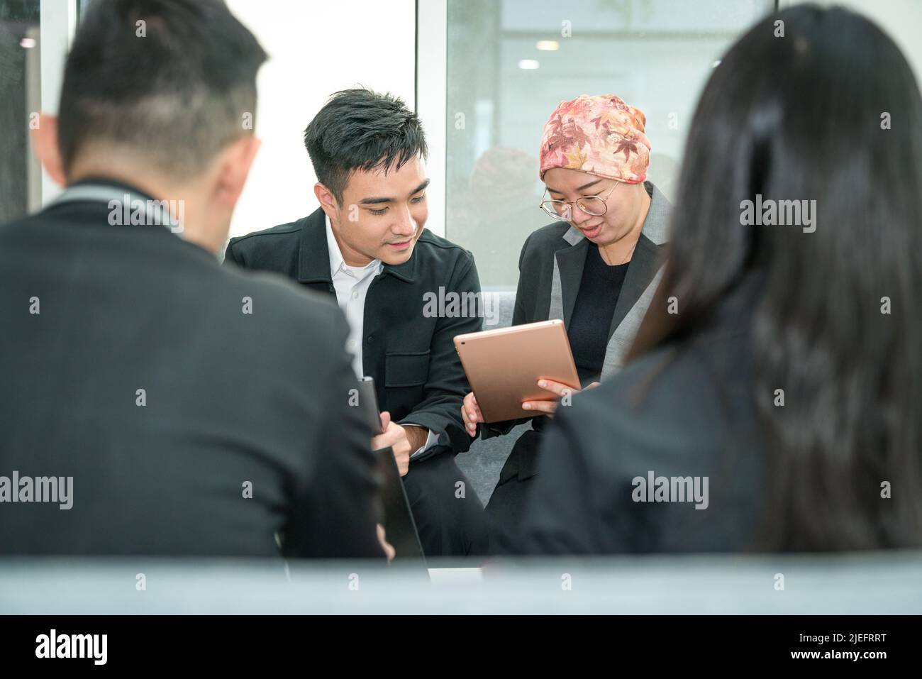 Colleghi di ufficio che guardano un tablet digitale durante una discussione. Foto Stock