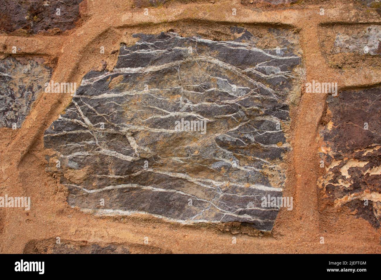 arancione sollevato puntando utilizzato tra la costruzione di pietra di edificio e. dettaglio delle striature nella roccia Foto Stock