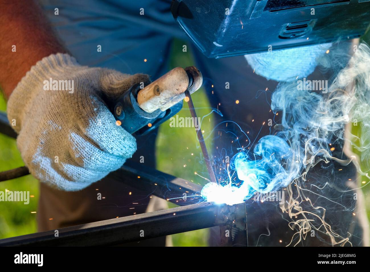 Scintille e fumo dalla saldatura metallica. Messa a fuoco selettiva. Saldatura di metalli mediante saldatura ad arco elettrica. Foto Stock