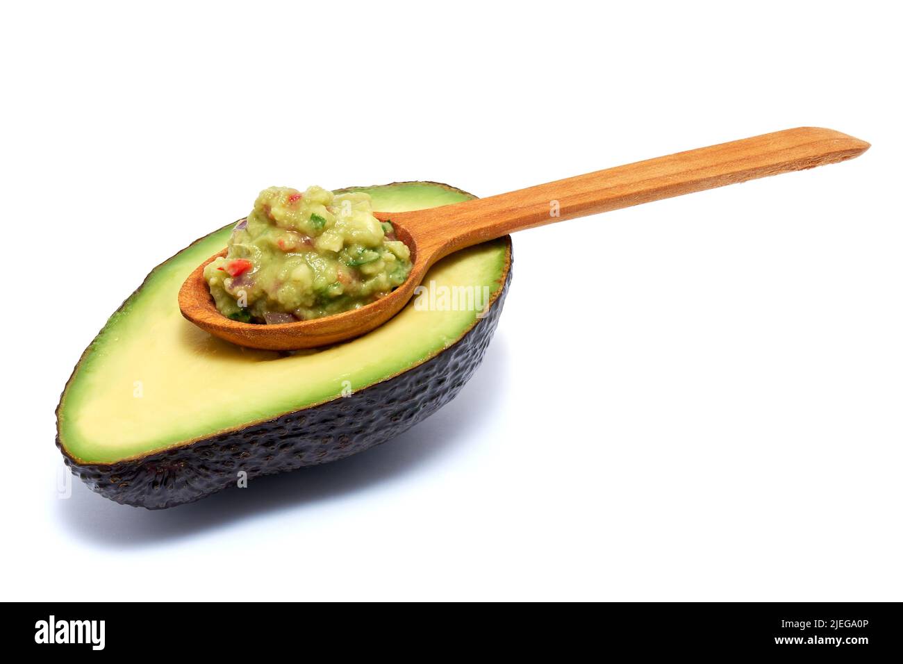 Cucchiaio di legno di salsa guacamole e metà di avocado isolato su sfondo bianco Foto Stock