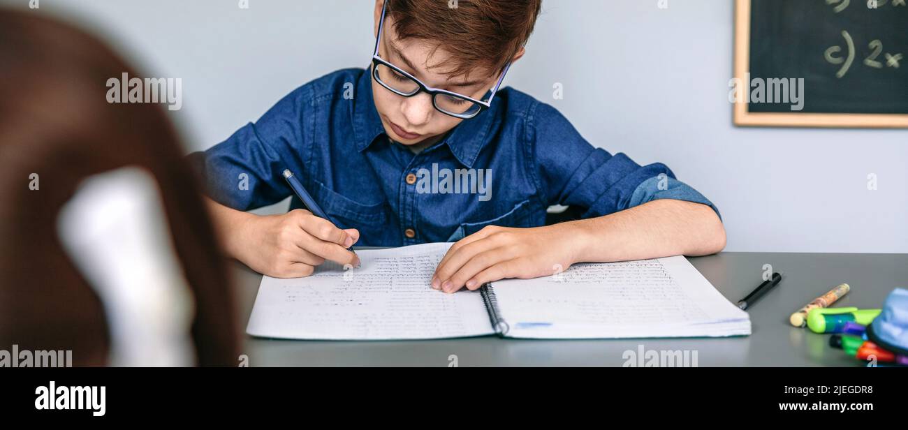 Teenager che scrive in taccuino a scuola Foto Stock