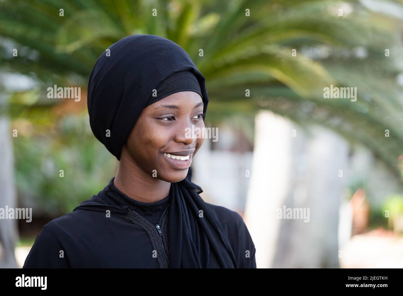 Giovane donna africana vestita di nero con un sorriso vincente e uno sguardo dolce Foto Stock