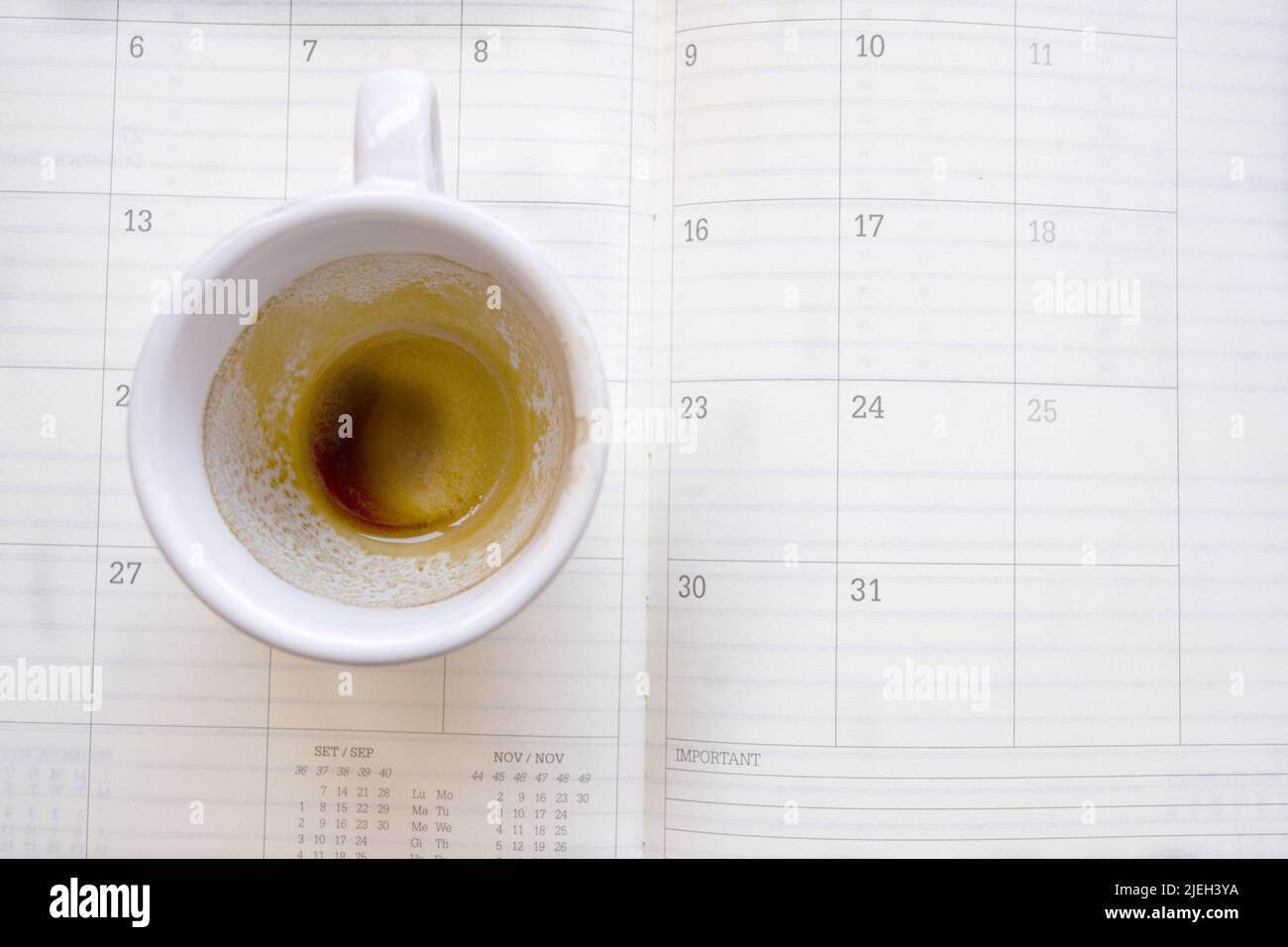 svuotare la tazza di caffè su un diario di lavoro Foto Stock