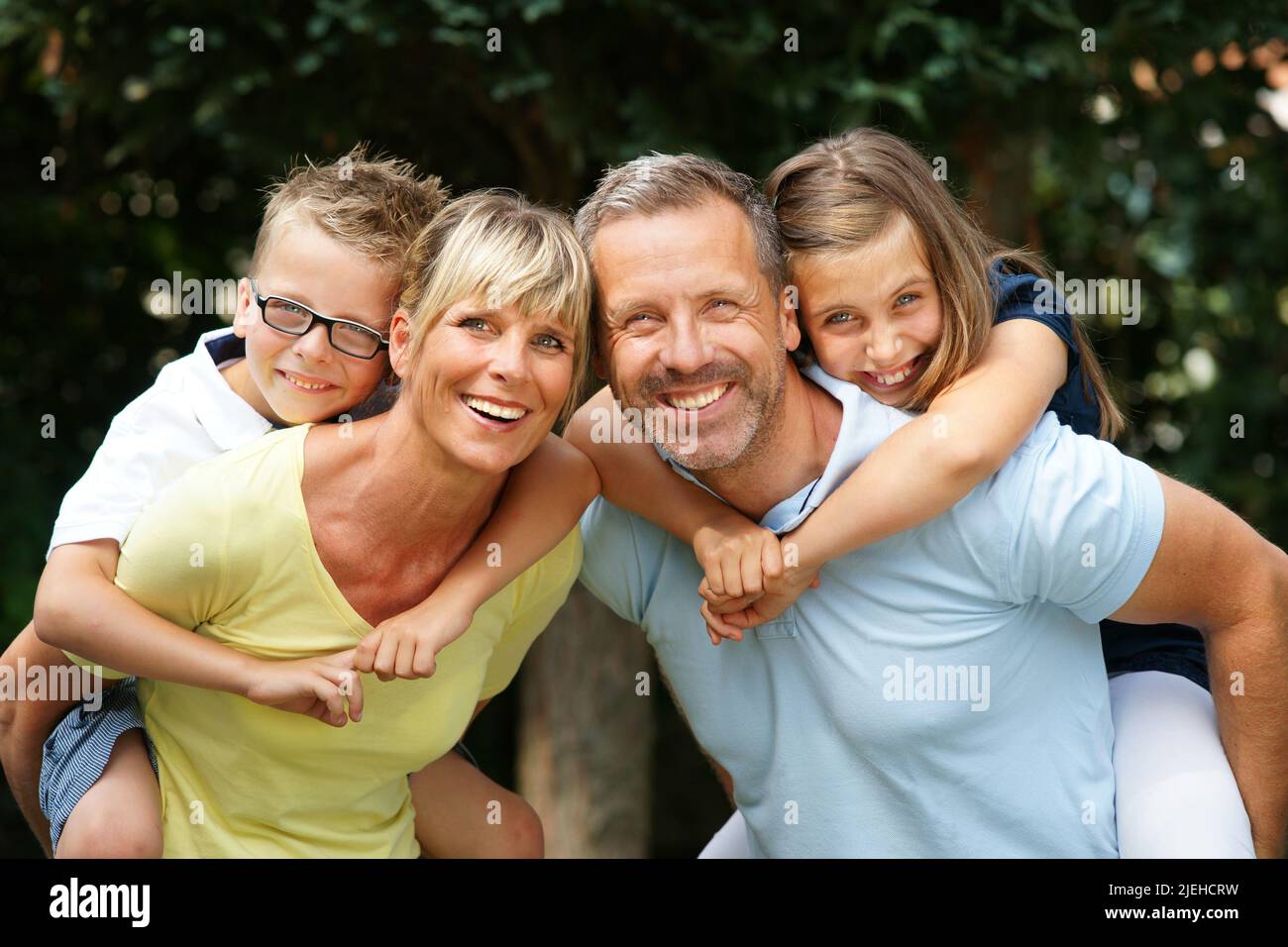 Eine glückliche Familie im Garten, 4 Personen, Eltern nehmen die Kinder Huckepack, Foto Stock